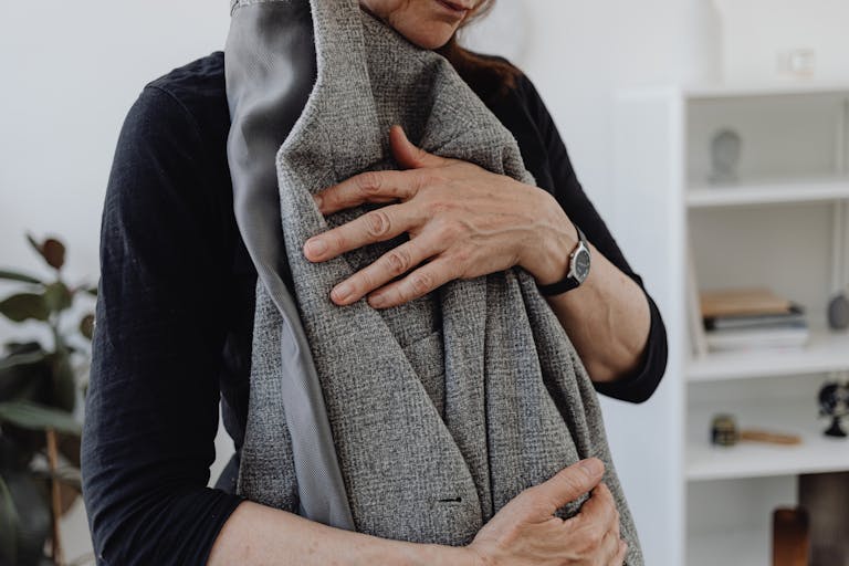 A woman embracing a blazer, symbolizing grief and loss, in a calming home setting.