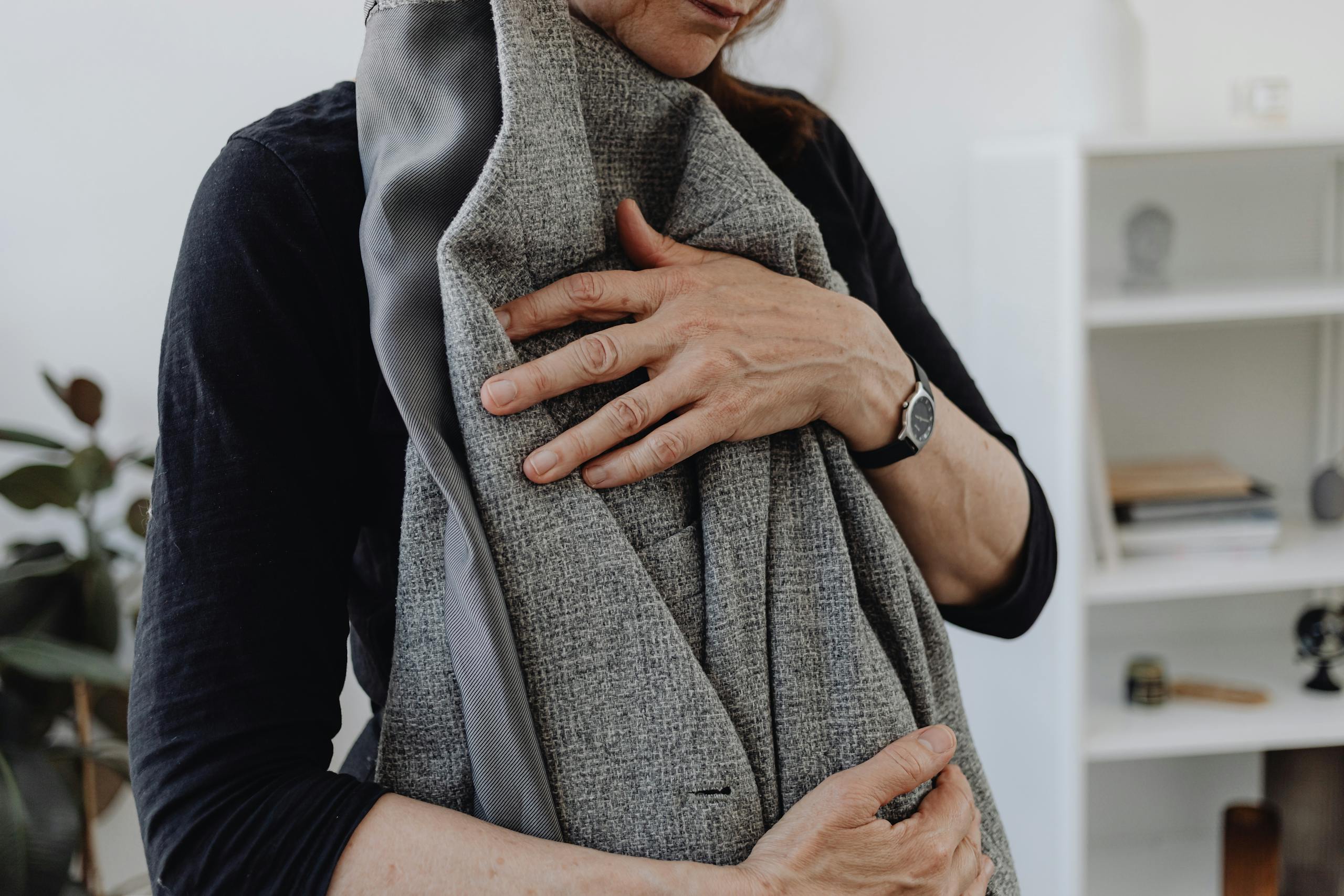 A woman embracing a blazer, symbolizing grief and loss, in a calming home setting.